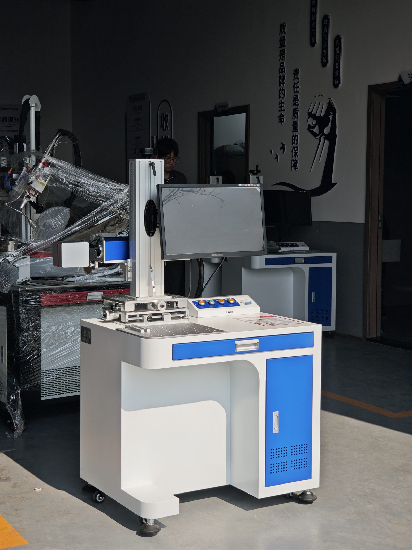 Side view of desktop fiber laser marker mounted alongside conveyor belt for side marking