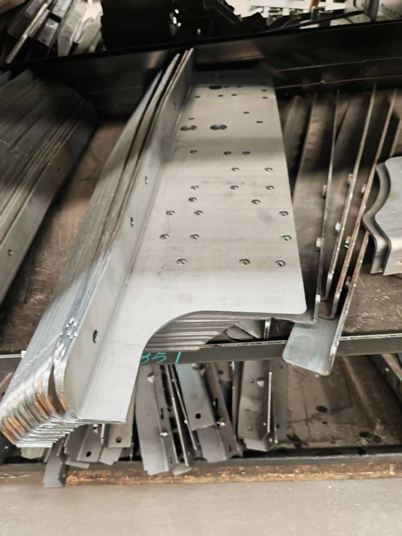 Long stamped automotive chassis rails and structural parts awaiting identification marking