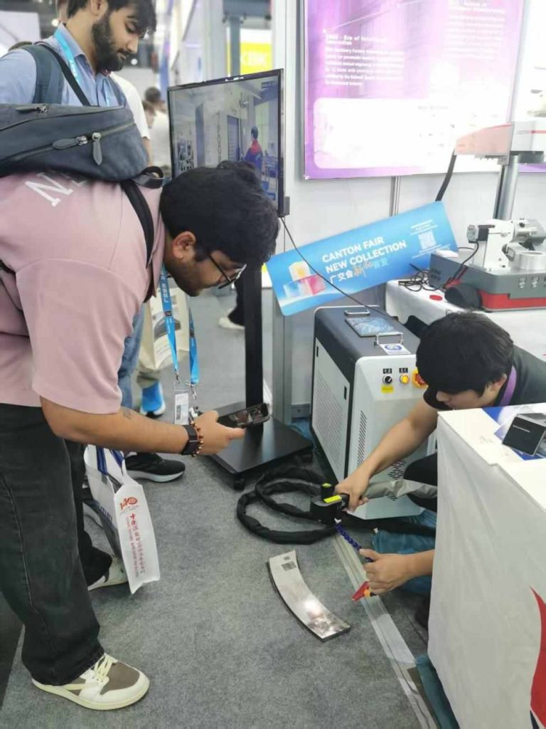 A visitor films the live laser cleaning demonstration at the Zixu booth